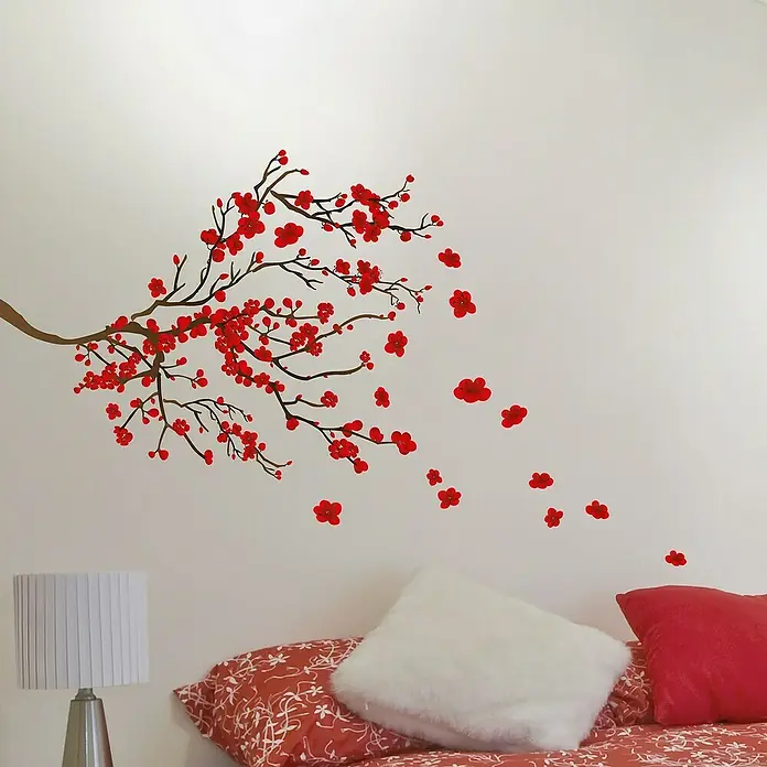 Vinilo de pared Ramas flores rojas - Rojo/Marrón, Plástico - Vinilo decorativo con diseño de árbol de flor roja sobre una pared blanca encima de una cama con cojines rojos y una lámpara.