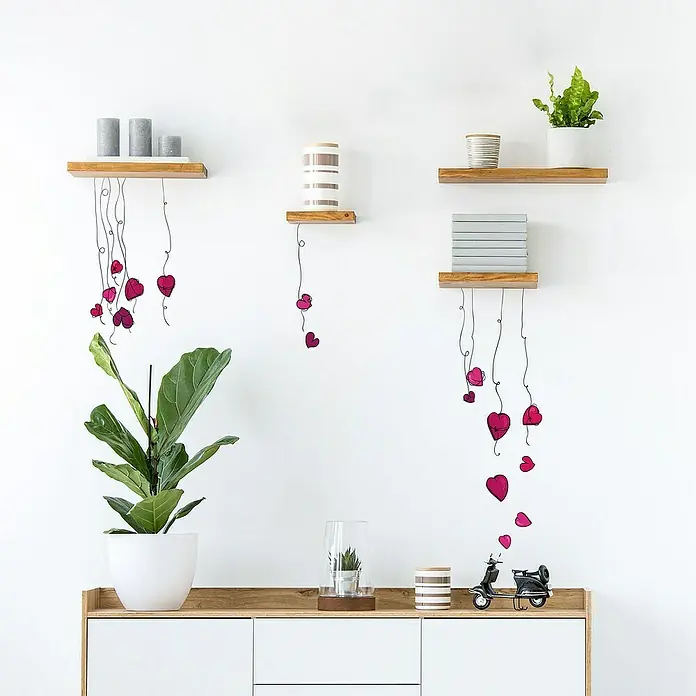 Vinilo de pared Corazones - Rojo, Plástico - Estantes de pared de madera con elementos decorativos como velas, plantas y corazones colgantes, creando un ambiente cálido y acogedor.