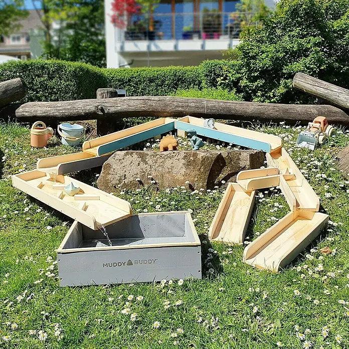 Muddy Buddy Wasserbahn Aqua Traveller - Holz, Natur/Wolkengrau - Das Muddy Buddy Wasserspielzeug mit Kaskadensystem auf einer grünen Wiese mit weißen Gänseblümchen bietet stundenlangen Spielspaß im Freien.