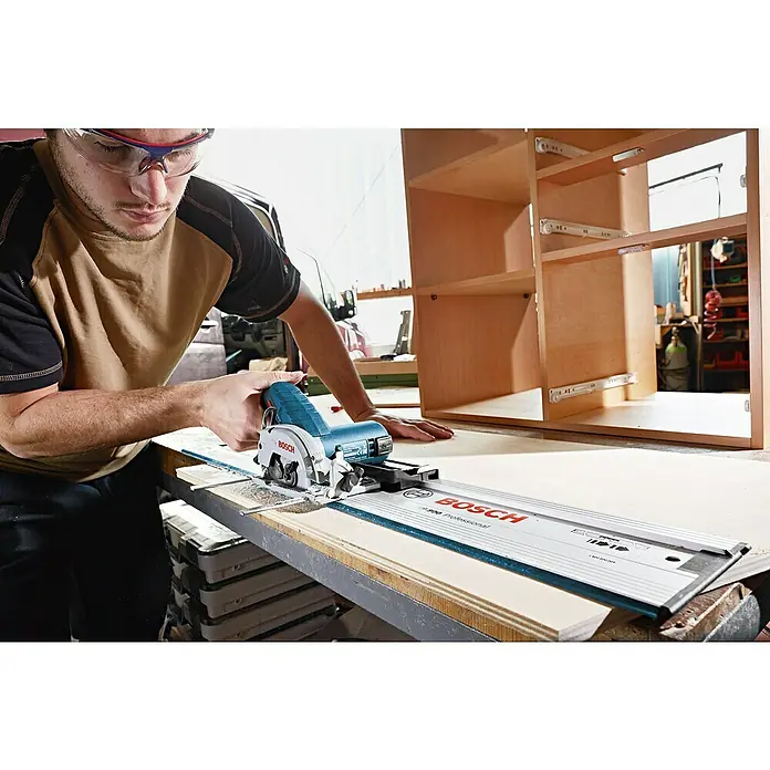 Bosch Professional Akku-Handkreissäge GKS 12V-26 - 12 V, Li-Ionen, Ohne Akku, Sägeblatt: 85 mm, 1.400 U/min - Ein Mann benutzt eine Bosch Tauchsäge mit Führungsschiene, um Holz zu schneiden. Der Fokus liegt auf dem Werkzeug und der präzisen Schnittführung.