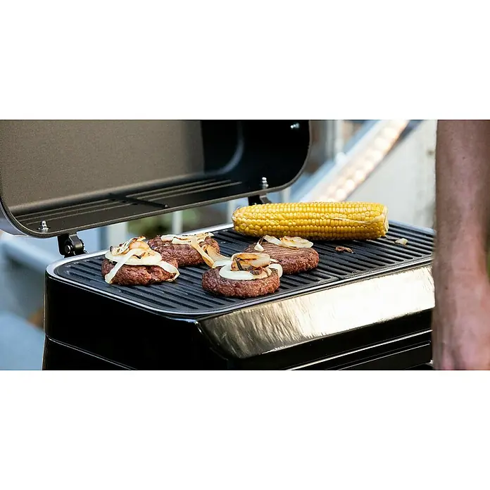 Campingaz Barbacoa de gas Attitude 2GO - Número de quemadores: 1 - Parrilla con hamburguesas y mazorcas de maíz. La parrilla es negra y tiene una tapa abierta.