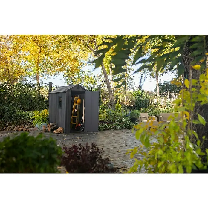 Keter Caseta de jardín Darwin 4x6 - Medidas ext. (An x Pr): 125,8 x 184,5 cm, Plástico, Gris, 2,3 m² - Un cobertizo gris con la puerta abierta se encuentra en una plataforma de madera, herramientas y una escalera son visibles en el interior.