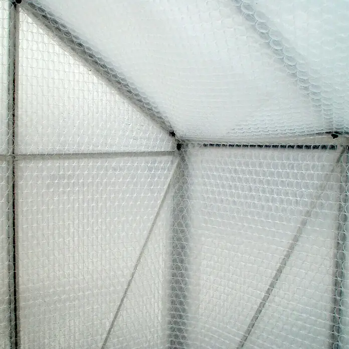 Juliana Folie - 10 x 1,5 m, Transparent - Innenansicht eines Gewächshauses mit einer Struktur aus Metallstreben und einer transparenten Blasenfolienabdeckung für Isolierung.
