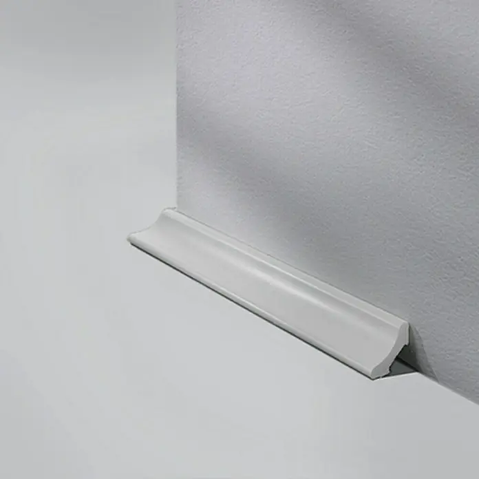 LOGOCLIC Hohlkehlleiste Hellgrau - 250 cm x 20 mm x 20 mm - Nahaufnahme einer weißen Fußleiste, die an einer hellgrauen Wand angebracht ist und einen sauberen Übergang zwischen Wand und Boden schafft.