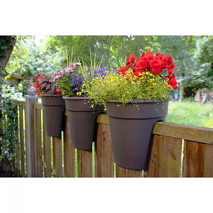KHW Geländertopf Flowerclip - Außenmaß (Ø x H): 27 x 27,5 cm, Kunststoff, Anthrazit - Drei dunkelgraue Kunststoff-Pflanzgefäße mit bunten Blumen, hängend an einem rustikalen Holzzaun.