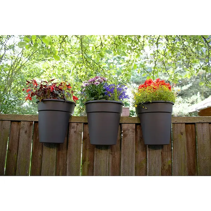 KHW Geländertopf Flowerclip - Außenmaß (Ø x H): 27 x 27,5 cm, Kunststoff, Anthrazit - Drei schwarze Pflanztöpfe mit bunten Blumen hängen an einem Holzzaun, der eine idyllische und farbenfrohe Gartendekoration darstellt.