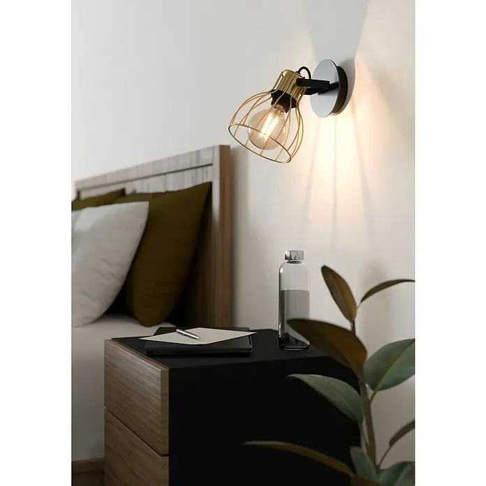 Eglo Sambatello Deckenstrahler - 40 W, L x B x H: 26 x 15 x 22 cm, Schwarz/Messing-gebürstet, E27, 1 Stk. - Ein goldenfarbene Wandleuchte mit einem Glühbirnen-Design beleuchtet ein modernes Schlafzimmer, das für eine gemütliche Atmosphäre sorgt.