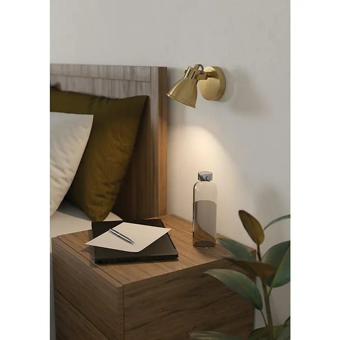 Eglo Seras Deckenstrahler SERAS - 3 W, Gold, GU10, 1 Stk. - Schlafzimmer-Szene mit einer goldenen Wandleuchte über einem Nachttisch mit Laptop, Papier und Stift sowie einer Wasserflasche.