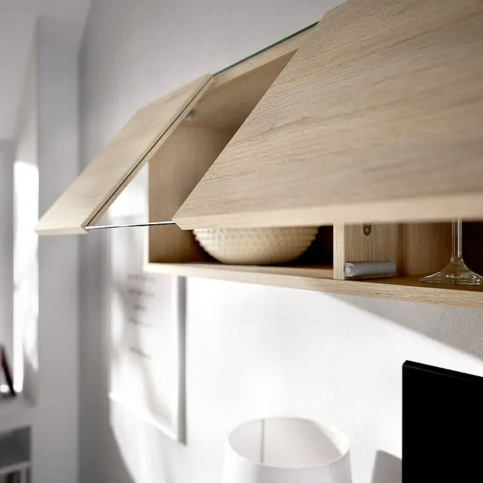 Dekit Conjunto mueble de salón Elle - Blanco brillo/Natural, 3 pzs. - Primer plano de un armario de pared de madera con frentes de vidrio que muestra un cuenco y una copa de vino, montado sobre un moderno mueble de TV.