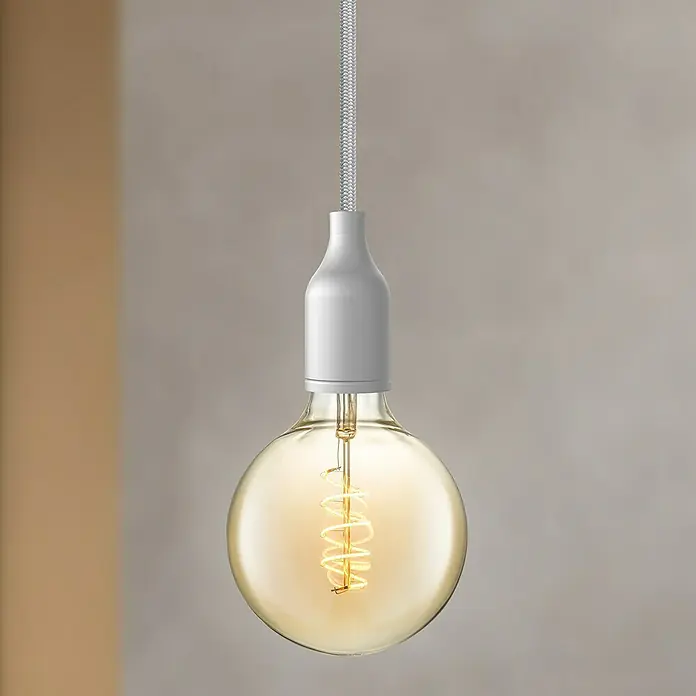 Home Sweet Home Textilkabel Meterware - Silber, 0,75 mm², 3 - Eine einzelne Edison-Glühbirne mit spiralförmigem Glühfaden hängt an einem weißen Kabel vor einem neutralen Hintergrund.