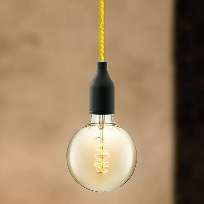 Home Sweet Home Textilkabel Meterware - Gelb, 0,75 mm², 3 - Nahaufnahme einer dekorativen Edison-Glühbirne mit gelbem Kabel und schwarzer Fassung vor einem braunen Hintergrund.