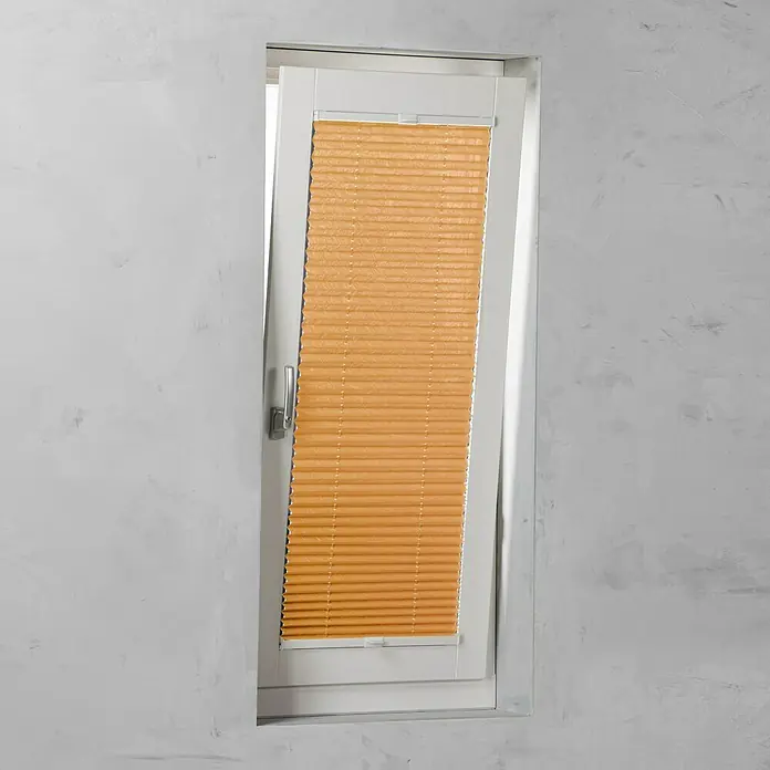 Expo Ambiente Plissee - B x H: 80 x 130 cm, Orange - Nahaufnahme einer geöffneten, orangefarbenen Jalousie, die in einem weißen Fensterrahmen angebracht ist, mit Blick auf die unebene, graue Wand.