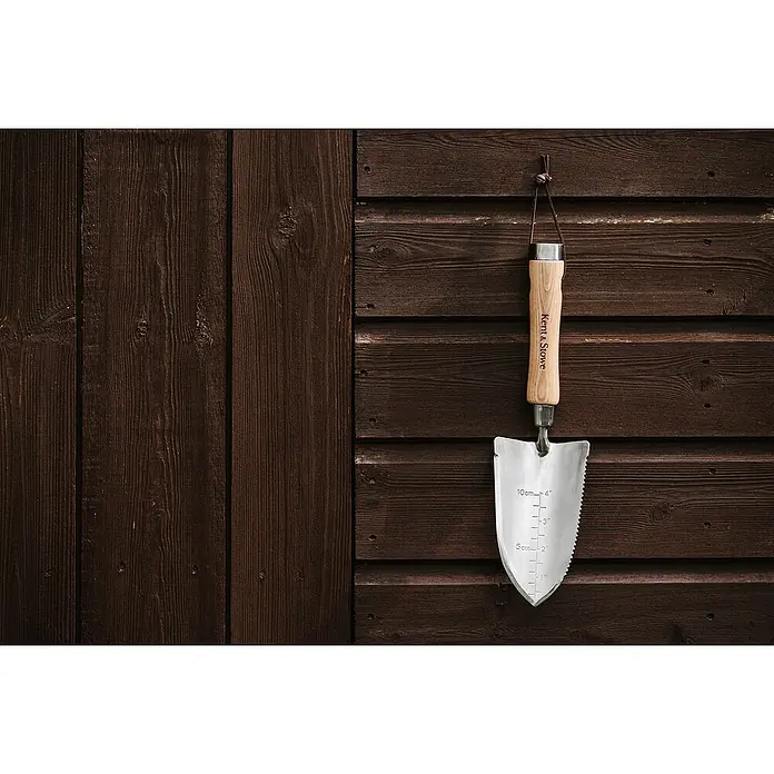 Kent & Stowe Blumenkelle - 32 cm - Nahaufnahme eines Kent & Stowe Gartenwerkzeugs, das an einer hölzernen Schuppenwand hängt.