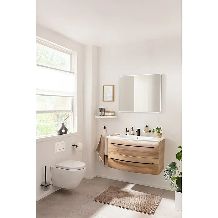 Camargue Swing K Beleuchtungs-Set - Länge: 90 cm - Ein modernes Badezimmer mit einem schwebenden Waschtisch aus hellem Holz und einem beleuchteten Spiegel. Die Einrichtung wirkt hell und freundlich.