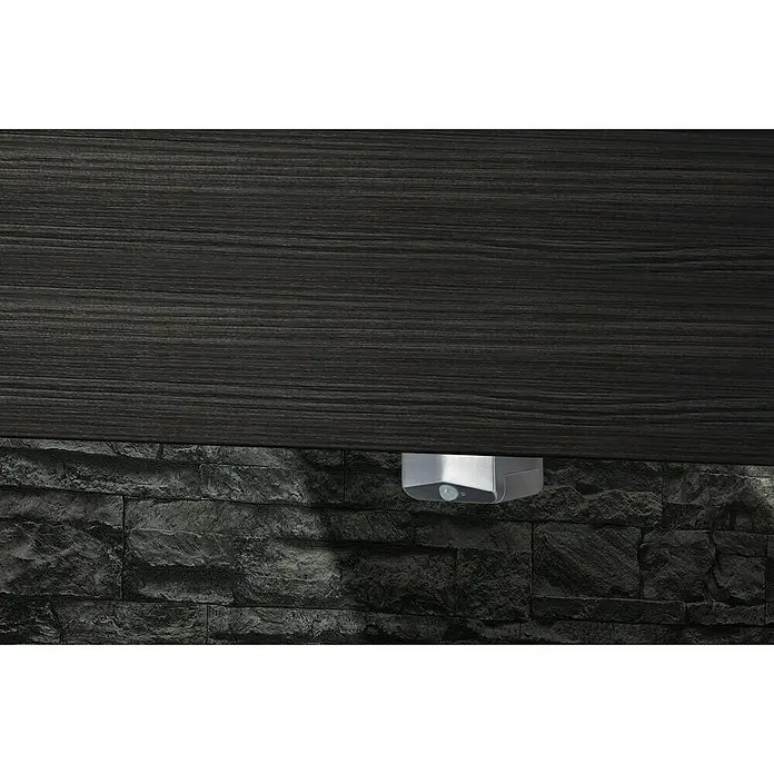 Camargue Swing K Beleuchtungs-Set - Länge: 120 cm - Detailaufnahme einer modernen Beleuchtungseinrichtung unter einem dunklen Holzregal, montiert an einer Wand mit dunklem Steinmuster.