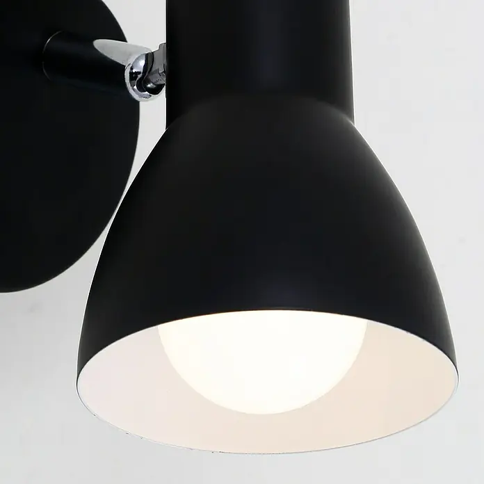 Briloner Cup Aplique de pared redondo - 25 W, Ø x Al: 8 x 13 cm, Negro, Negro, E14 - Primer plano de una moderna lámpara de pared negra con interior blanco, que emite una luz brillante.\n