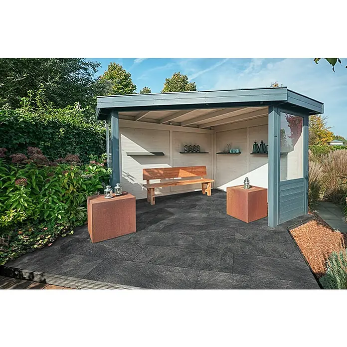 Granulati Zandobbio Terrassenfliese Cera 2.0 - 40 x 120 x 2 cm, Museo Ardesia Nero, Matt - Eine überdachte Terrasse mit einem schönen Holzbänkchen und zwei würfelförmigen Tischen mit Deko-Laternen, die ein entspannendes Ambiente schaffen.