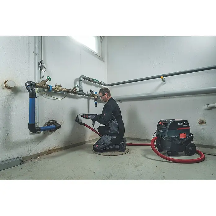 Metabo Kombihammer KHE 2445 - 800 W, 2,4 J, SDS-Plus-Aufnahme - Mann arbeitet mit einem Metabo ASR 35 ACP Staubsauger in einem Kellerraum, um Staub zu entfernen. Das Gerät ist robust und leistungsstark.