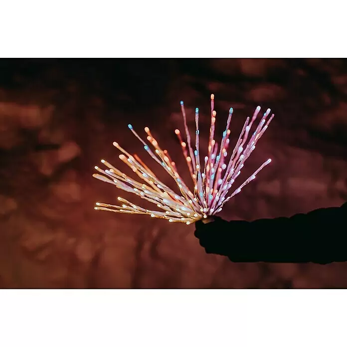 Twinkly LED-Dekoleuchte Spritzer - Netzbetrieben - Eine Hand hält ein leuchtendes Bündel LED-Lichtzweige mit blauen, rosa, orangefarbenen und weißen Lichtern, die ein festliches Leuchten erzeugen.