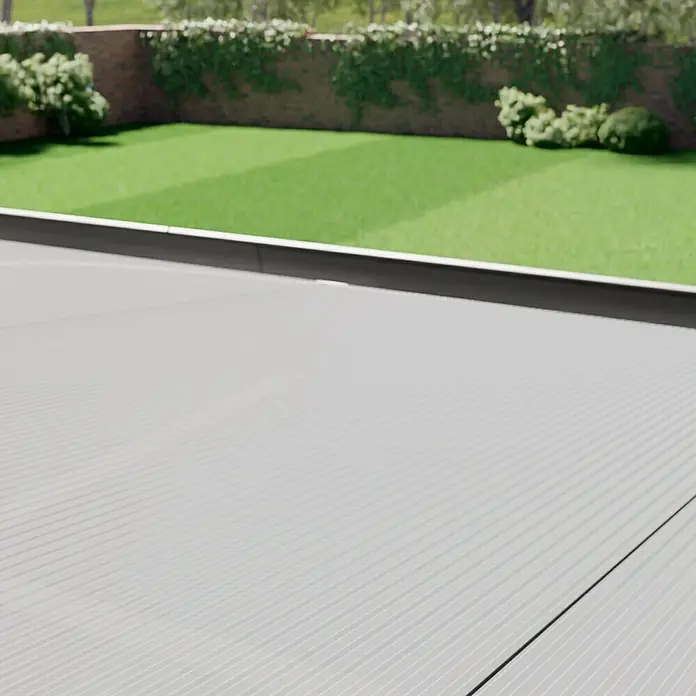 Gardendreams Terrassenüberdachung Comfort - B x T: 304 x 250 cm, Anthrazitgrau, Polycarbonat, Transparent - Eine ebene, strukturierte Fläche, wahrscheinlich ein Terrassenboden, in einem Garten mit grüner Rasenfläche und Büschen.