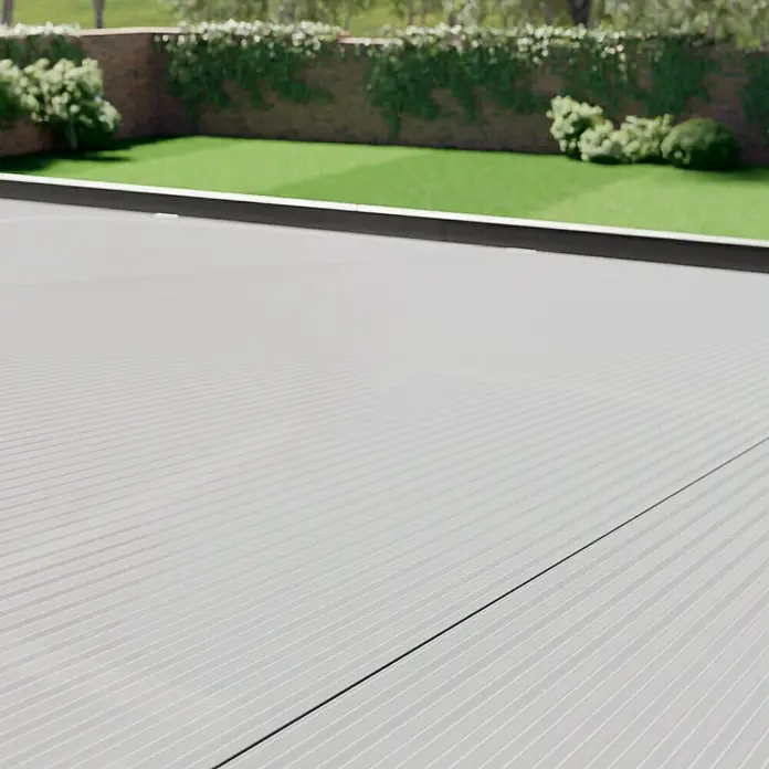 Gardendreams Terrassenüberdachung Comfort - B x T: 544 x 300 cm, Anthrazitgrau, Polycarbonat, Transparent - Nahaufnahme einer Oberfläche mit gerippter Textur und einem unscharfen Hintergrund mit Grünflächen und Pflanzen.