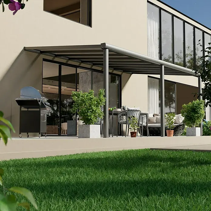 Gardendreams Terrassenüberdachung Comfort - B x T: 544 x 300 cm, Anthrazitgrau, Polycarbonat, Transparent - Blick auf eine moderne Terrassenüberdachung mit Grill, Sitzmöbeln und Pflanzenkübeln vor einem modernen Haus.