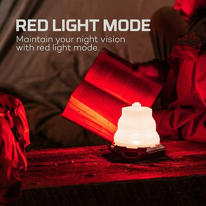 Nebo Tools Linterna Galileo Air - 12 x 12 x 11,8 cm, 40 lm - 1.000 lm, IPX4 - Una linterna LED plegable con modo de luz roja ilumina un libro sobre una mesa de madera. Ideal para camping y actividades al aire libre.