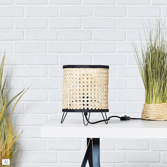 Brilliant Wiley Tischleuchte - 60 W, Schwarz, E27 - Tischlampe mit einem Lampenschirm aus Rattan und einem schwarzen Metallfuß auf einem weißen Tisch.