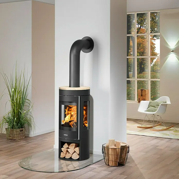Justus Kaminofen Mino Trios 2.0 - 5,5 kW, Raumheizvermögen: 88 m³, Farbe Verkleidung: Sandstein, Schwarz - Moderner Kaminofen mit Glasbodenplatte und Holzkorb für gemütliche Wärme im Wohnraum.