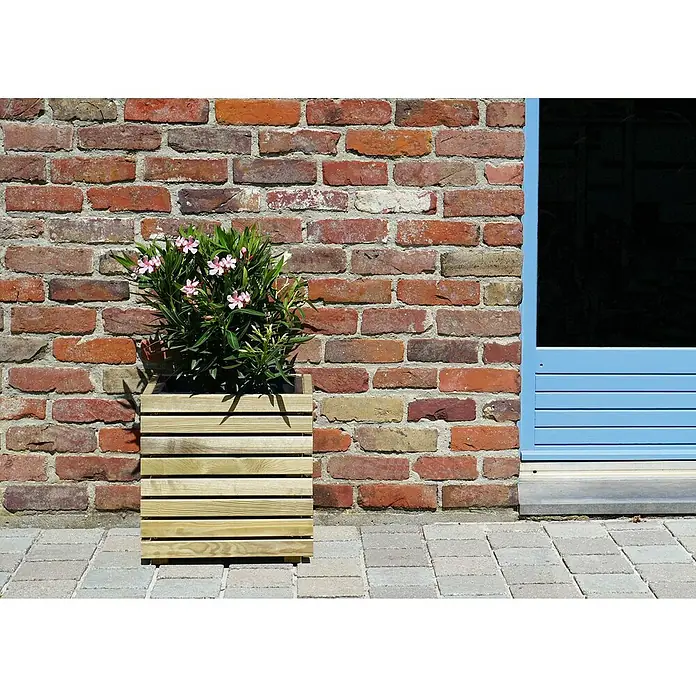 Cerland Macetero para plantas Horizon - Dimensiones externas (L x An x Al): 32,5 x 40 x 39,4 cm, Natural - Jardinera de madera con plantas de flores rosas contra una pared de ladrillos, al lado de una puerta azul, añadiendo un toque de elegancia.