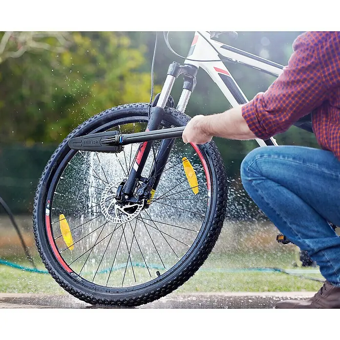 Nilfisk Hidrolimpiadora de alta presión CORE 140IH PCC - 140 bar, 1.800 W, Capacidad de bombeo: 474 l/h - Una persona limpia una bicicleta con un cepillo de lavado Nilfisk, centrándose en la limpieza eficaz del neumático de la bicicleta.