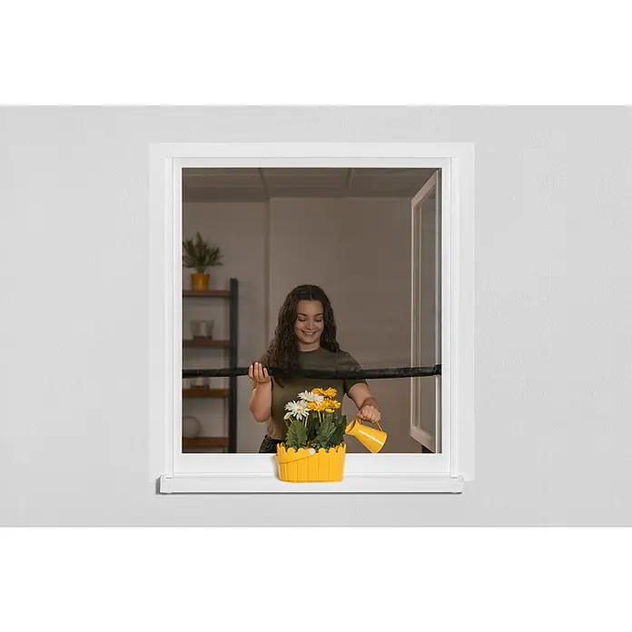 Schellenberg Mosquitera Easy Open - An x Al: 130 x 150 cm, Montaje de la mosquitera: Enganche, Color bastidor: Antracita - Mujer riega margaritas amarillas y blancas en una cesta amarilla frente a una ventana blanca.
