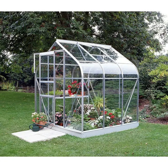 Vitavia Gewächshaus Orion 3800 - Außenmaß inkl. Dachüberstand (B x T): 202 x 195 cm, 3 mm, Silbergrau - Ein Gewächshaus aus Glas und Metall, gefüllt mit verschiedenen Pflanzen und Blumen, steht im Garten. Es bietet Schutz und ideale Wachstumsbedingungen.