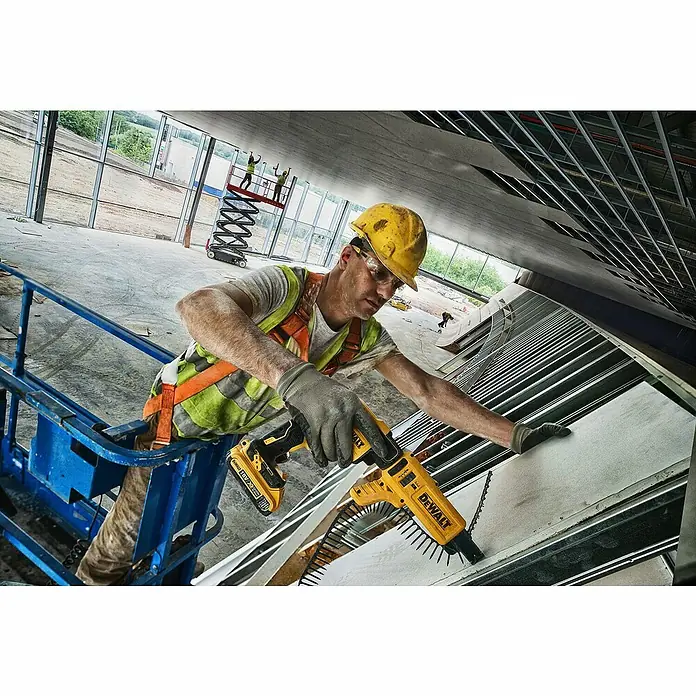 DeWalt Atornillador para placas de yeso de batería DCF620D2-QW - 18 V, 2 baterías, 2 Ah, 30 Nm - Un trabajador de la construcción utiliza un destornillador amarillo DeWalt para fijar un panel al techo de una obra.