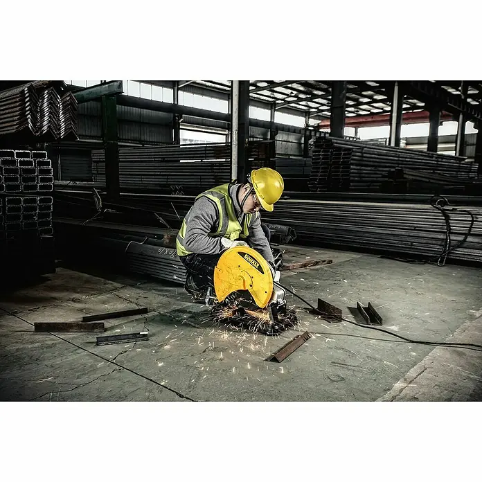 DeWalt Tronzadora D28730-QS - 2.200 W, Diámetro hoja de sierra: 355 mm, Número de revoluciones de marcha en vacío: 4.000 r.p.m. - Un trabajador de la construcción utiliza una tronzadora DeWalt en una fábrica para cortar metal, con muchas chispas volando.
