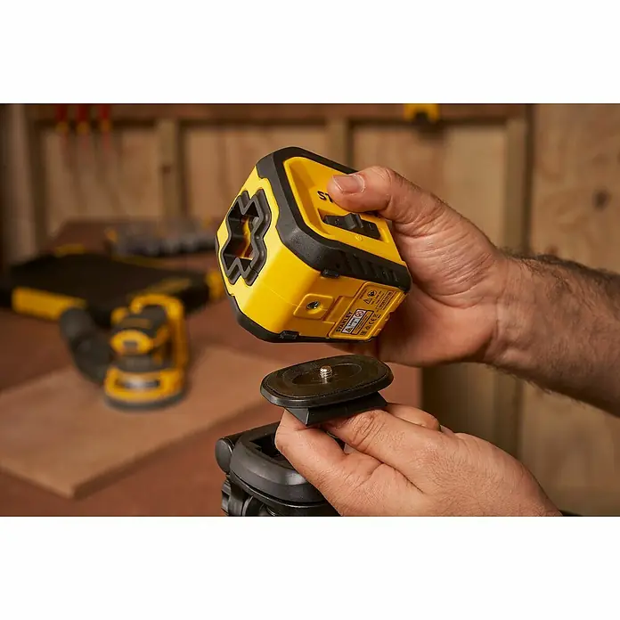 Stanley Nivel láser en cruz STHT77611-0 - Zona de trabajo máx.: 10 m - Primer plano de un láser Stanley amarillo que se está fijando a un soporte negro, perfecto para tareas de nivelación precisas.
