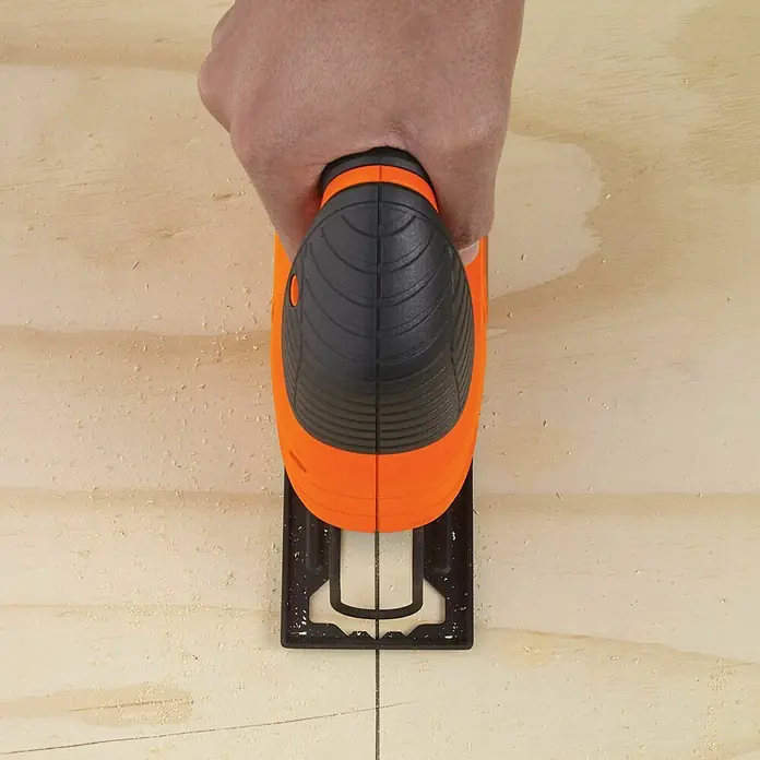 Black+Decker Elektro-Stichsäge KS501-QS - 3.000 /min, 65 mm - Eine Nahaufnahme einer Stichsäge, die von einer Hand gehalten wird, die ein Holzbrett zuschneidet, wobei der Fokus auf der Säge liegt.