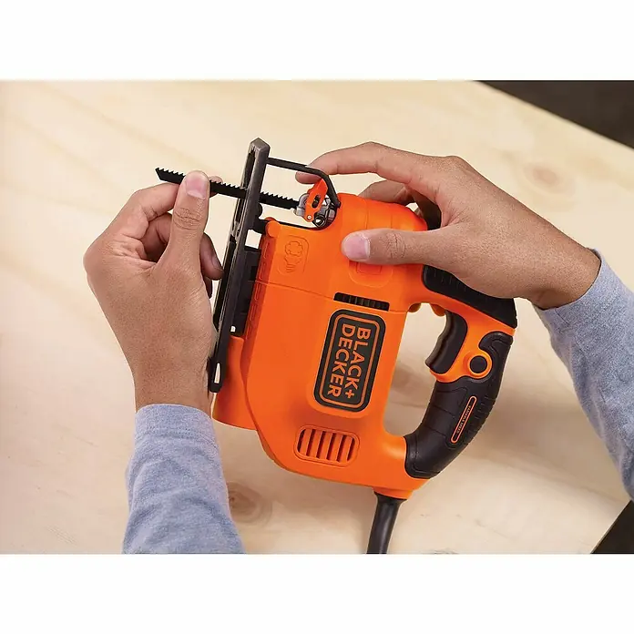 Black+Decker Caladora eléctrica KS701PEK-QS - 3.000 /min, Profundidad de corte máx. en madera: 70 mm, Número de niveles de elevación del péndulo: 4 ud. - Un hombre inserta una hoja en una sierra de calar Black+Decker naranja para proyectos de corte de madera precisos.