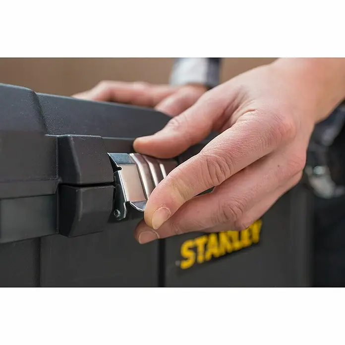 Stanley Caja para herramientas STST1-80150 - L x An x Al: 34,4 x 66,5 x 40,4 cm, Polipropileno, Capacidad volumétrica: 50 l - Primer plano de una caja de herramientas Stanley, mostrando la mano abriendo el cierre resistente, destacando su diseño y funcionalidad.