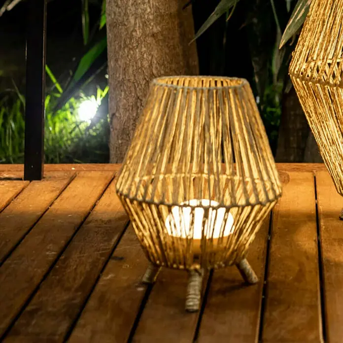 New Garden Sisine Außenstehleuchte Sisine - B x H: 25,5 x 32,5 cm - Die Lampe im natürlichen Design sorgt für eine stimmungsvolle Beleuchtung. Sie steht auf einem Holztisch und strahlt warmes Licht aus.