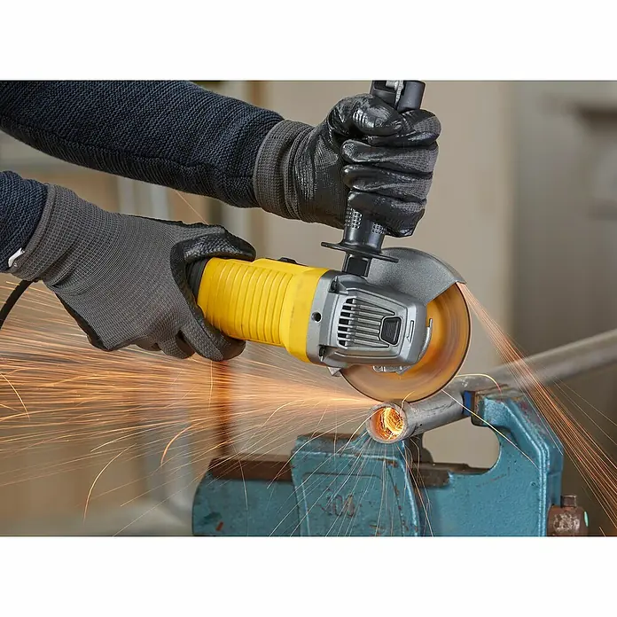 Stanley FatMax Elektro-Winkelschleifer FMEG220-QS - 850 W, 125 mm, 12.000 U/min - Ein Winkelschleifer in Aktion beim Schneiden eines Metallrohrs, wobei Funken sprühen und die Schutzkleidung des Bedieners sichtbar ist.