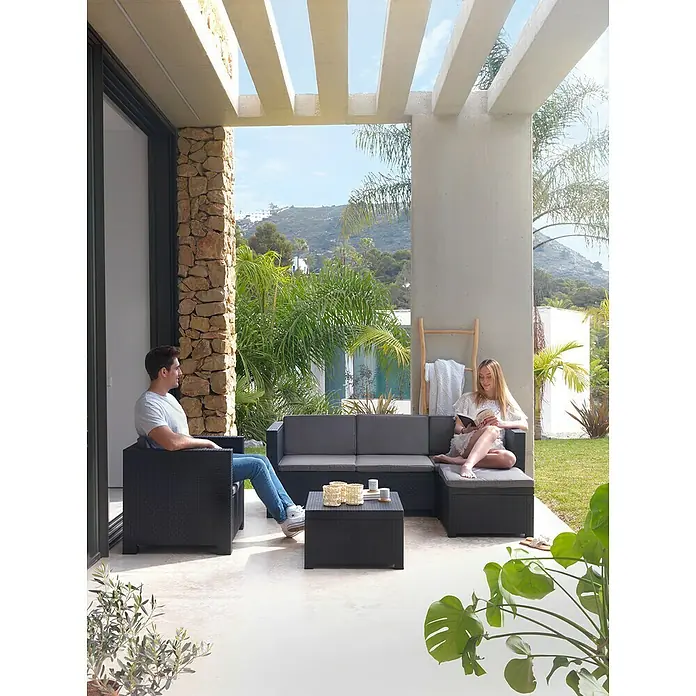 Shaf Conjunto de muebles Manhattan - 3 pzs., Polipropileno, Graphite - Pareja relajada disfruta del moderno juego de muebles de patio negros con cojines grises en la terraza con vistas al paisaje verde.
