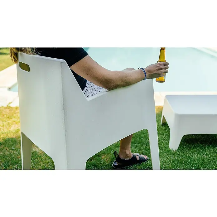 Silla de jardín Master - 60 x 67 x 82 cm, Blanco, Polipropileno, Apilable - Una persona relajándose en una silla blanca de exterior con una cerveza, complementada con una mesa a juego al lado.