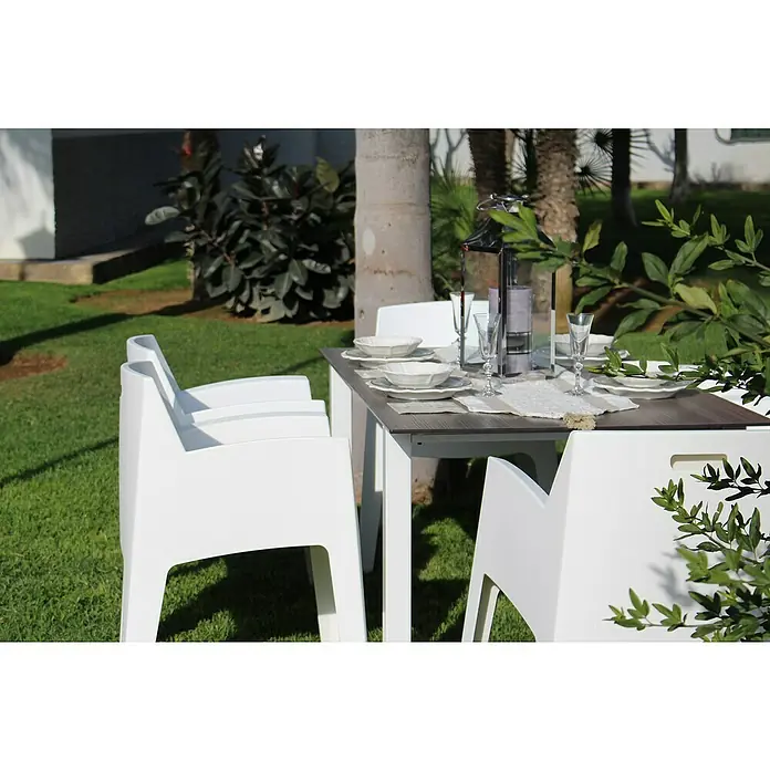 Silla de jardín Master - 60 x 67 x 82 cm, Blanco, Polipropileno, Apilable - Una mesa de jardín con estructura blanca y tablero oscuro está puesta con platos y vasos para una comida al aire libre.