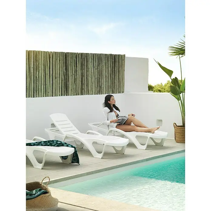 Tumbona de jardín Salerno - 65 x 195 x 43 cm, Blanco, Plástico, Respaldo regulable - Tres tumbonas blancas de plástico situadas junto a la piscina, una con una mujer leyendo, que ofrecen relajación y confort junto a la piscina.