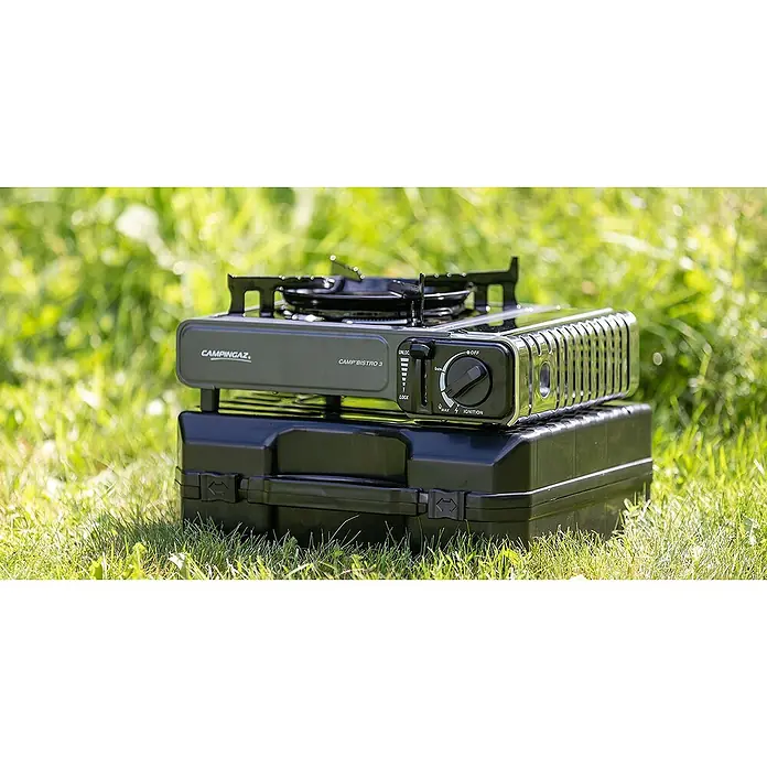 Campingaz Hornillo de gas Bistro 3 - L x An x Al: 36 x 32 x 13,7 cm, 2,2 W, Número de quemadores: 1 ud. - Fogón Campingaz Bistro 3 con maletín de transporte negro en el exterior sobre hierba. Ideal para viajes de camping, fácil de transportar y usar.