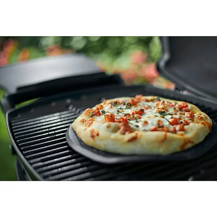 Weber Barbacoa de gas Q2200 - Superficie de la parrilla (An x Pr): 54 x 39 cm, 3,52 kW, Número de quemadores: 1 - Una deliciosa pizza sobre una piedra de pizza que se está preparando en una parrilla, cubierta con queso fundido e ingredientes frescos.