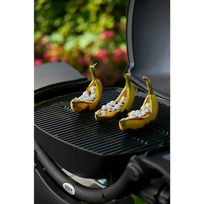 Weber Barbacoa de gas Q2200 - Superficie de la parrilla (An x Pr): 54 x 39 cm, 3,52 kW, Número de quemadores: 1 - Tres plátanos rellenos de malvaviscos en una parrilla Weber, los plátanos están partidos por la mitad y listos para asar.