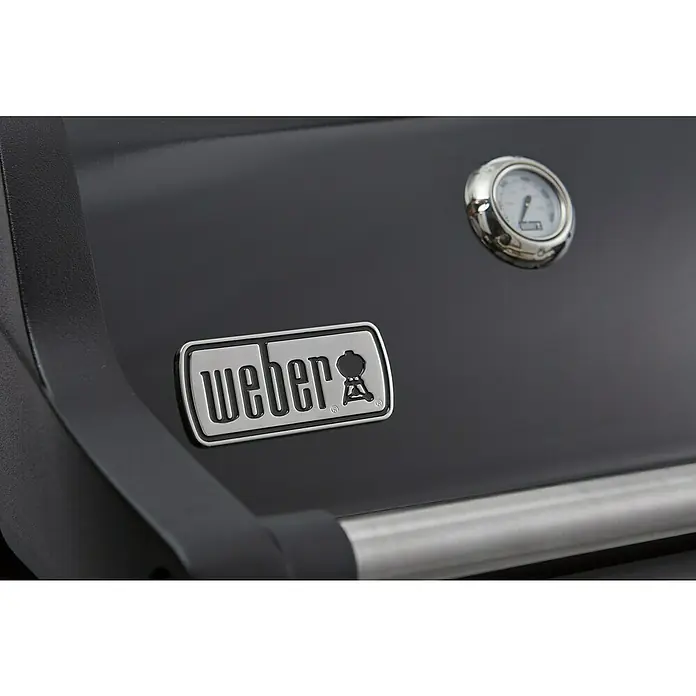 Weber Barbacoa de gas Spirit E-215 GBS - Superficie de la parrilla (An x Pr): 52 x 45 cm, Número de quemadores: 2 - Primer plano de una barbacoa Weber, mostrando el logotipo de Weber y un termómetro, destacando su construcción de calidad y funcionalidad.