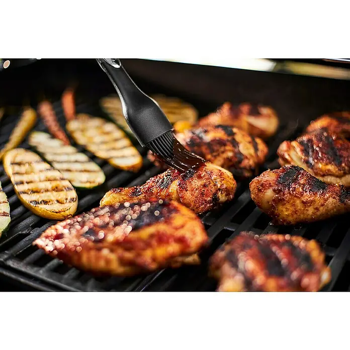 Weber Barbacoa de gas Spirit E-215 GBS - Superficie de la parrilla (An x Pr): 52 x 45 cm, Número de quemadores: 2 - Piezas de pollo se untan con salsa en la parrilla con un pincel negro, junto a calabacines a la parrilla.